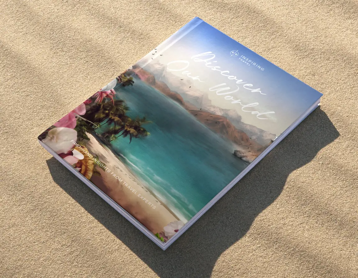 Travel book titled 'Discover Our World' with a tropical beach and ocean scene on the cover, lying on sand.