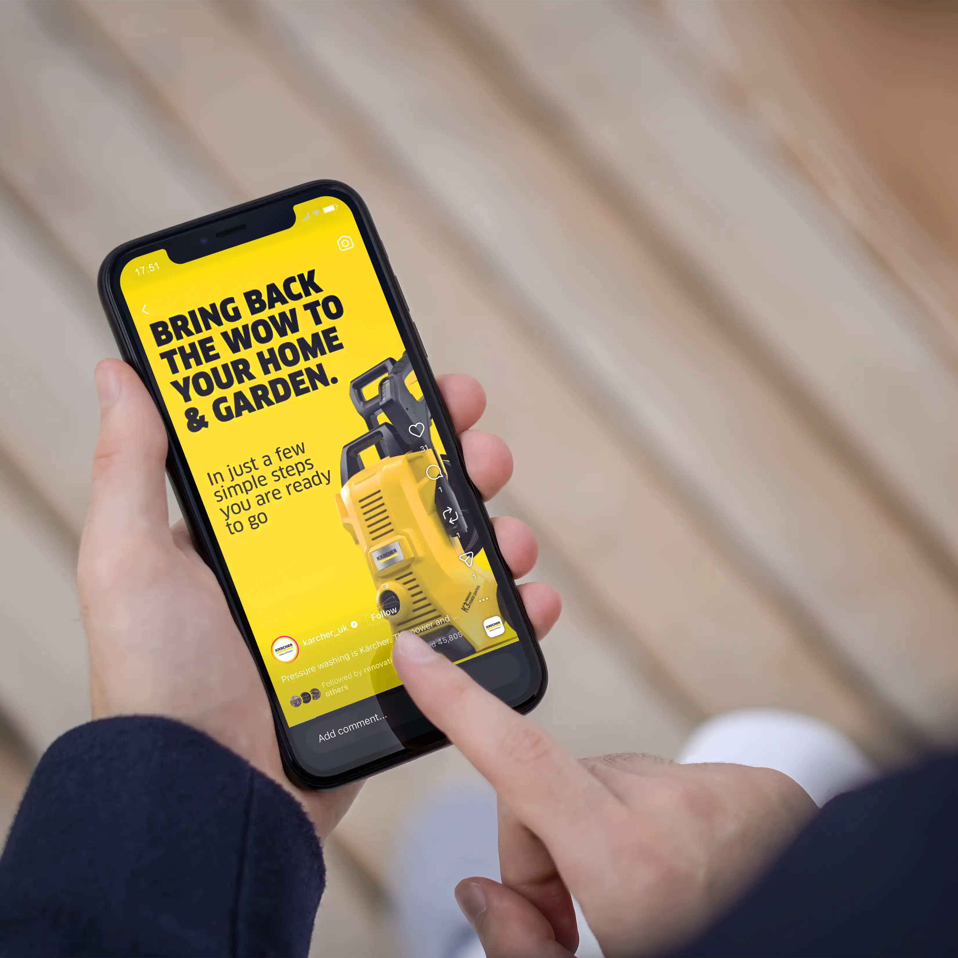 Person holding smartphone displaying ad for Kärcher pressure washers with yellow background and black text.