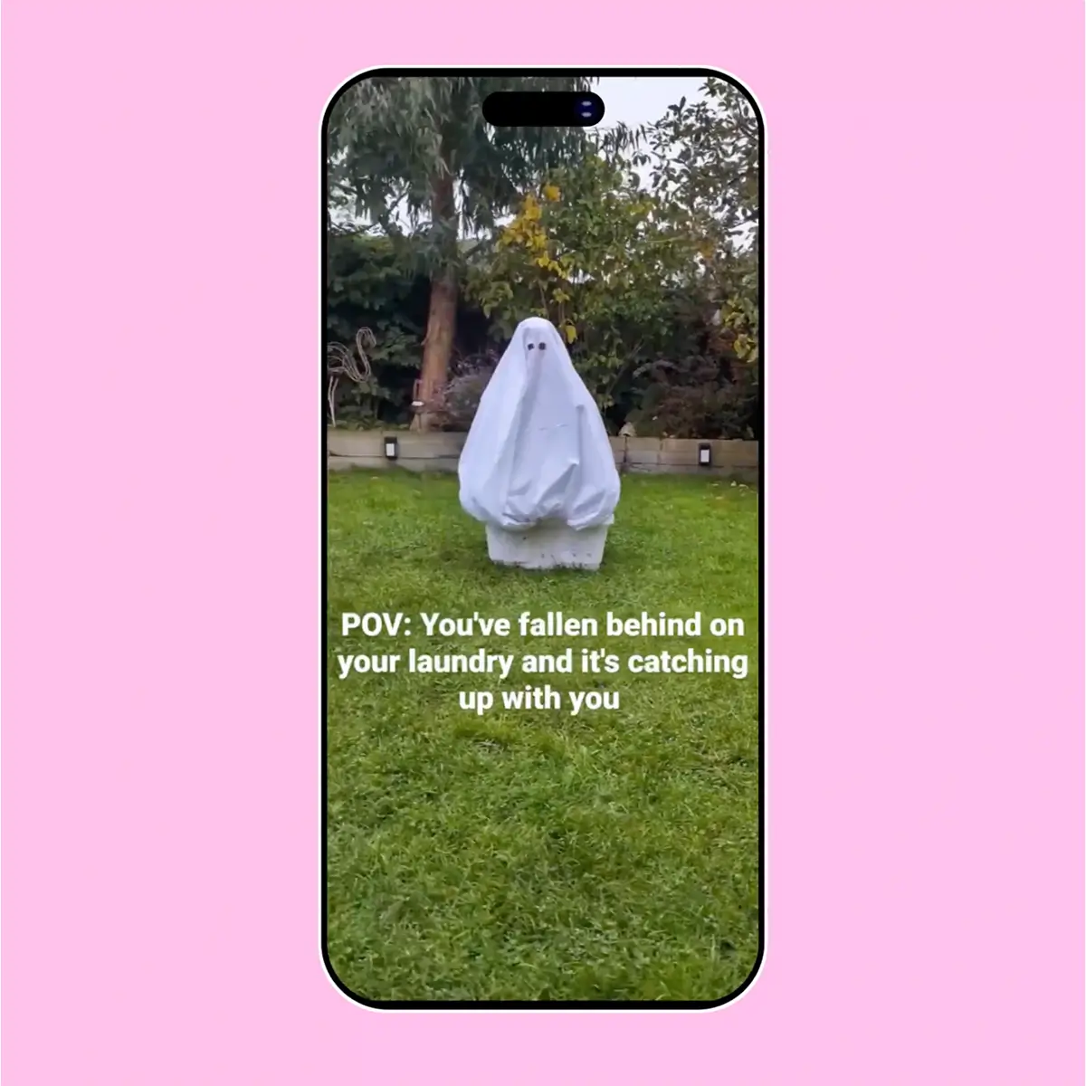 Phone screen showing a person covered in a white sheet like a ghost on grass with text about laundry piling up.