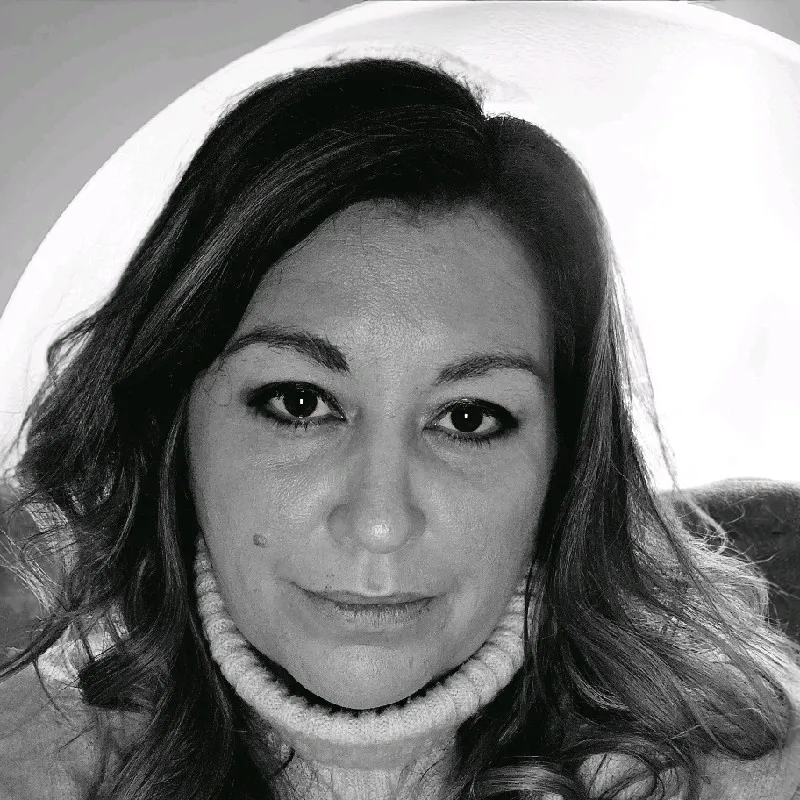 Black and white portrait of a woman with light wavy hair wearing a knitted turtleneck sweater.