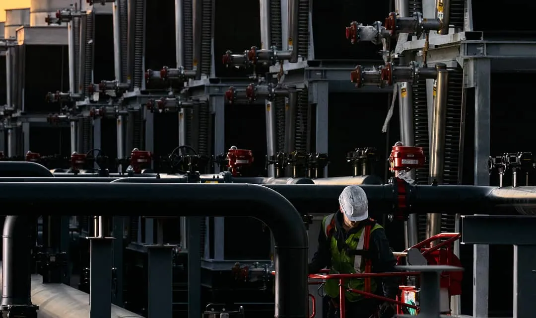 Technician working among valves and pipework on TeraWulf data center cooling infrastructure.