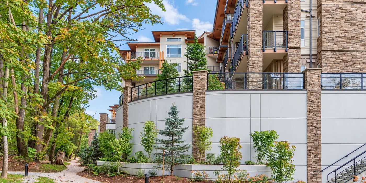 Apartment building with stone columns, private balconies, and a landscaped walkway.