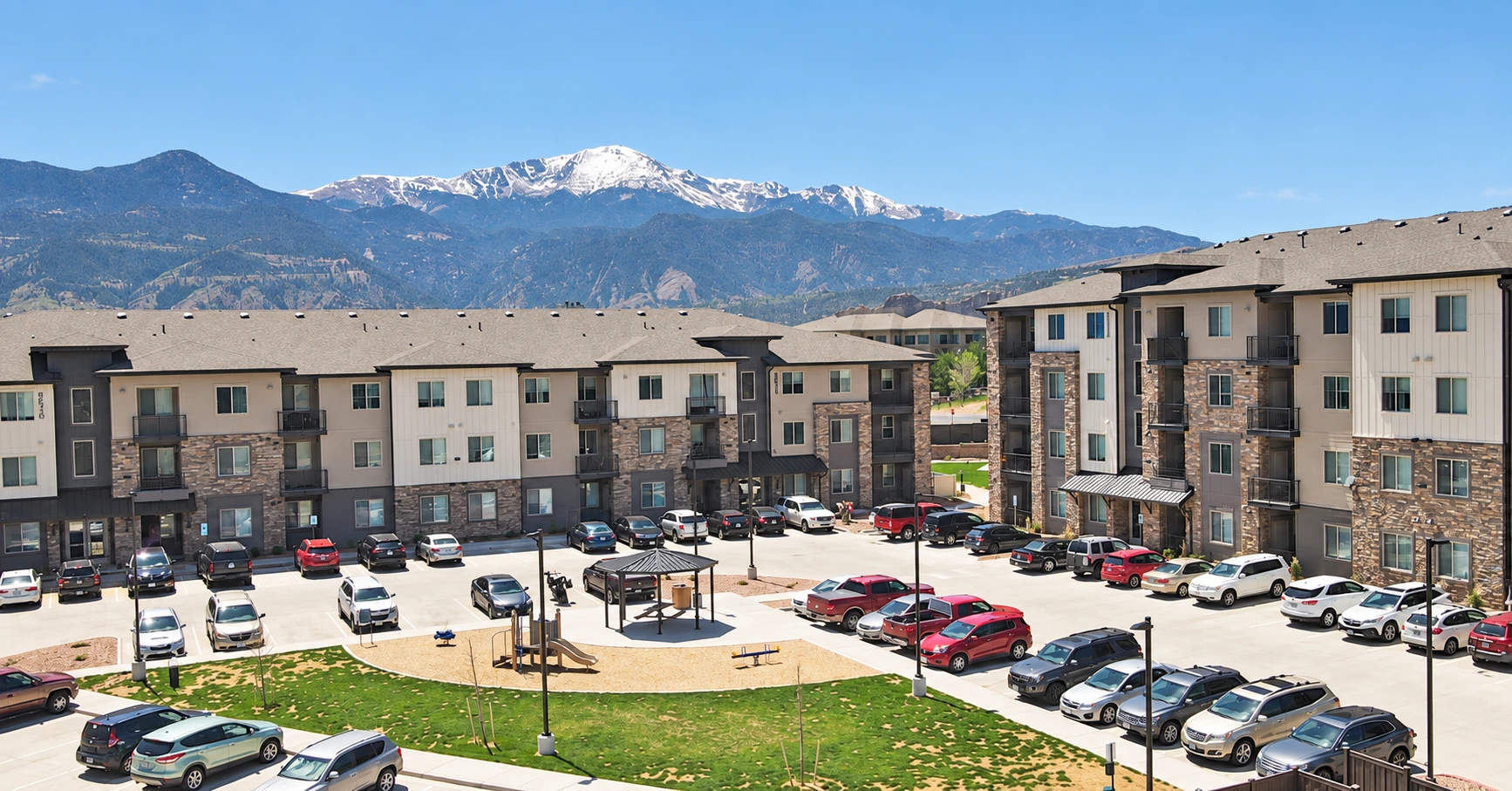 Apartment buildings around a shared courtyard, with mountains in the background.