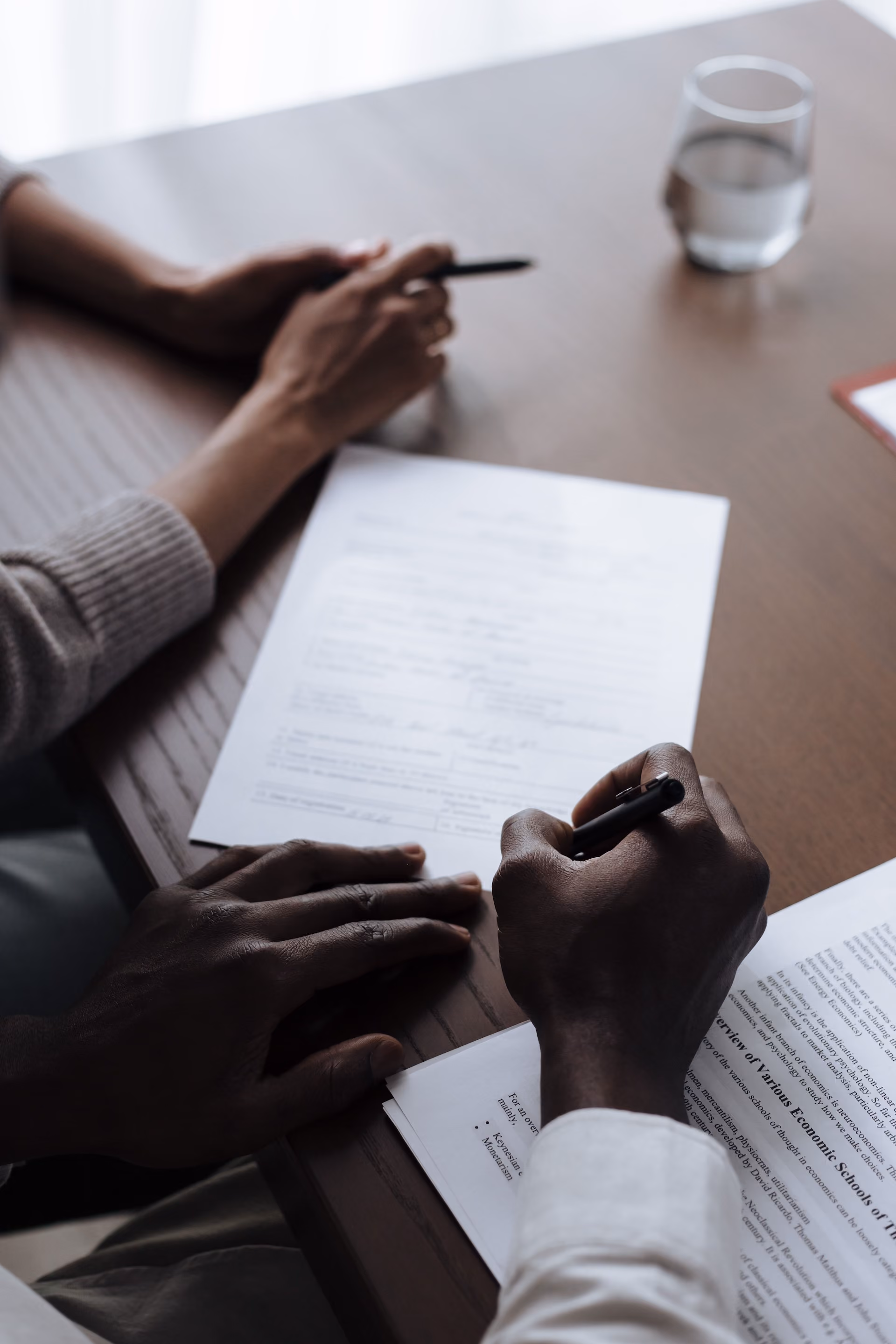 Hands on table signing a document.