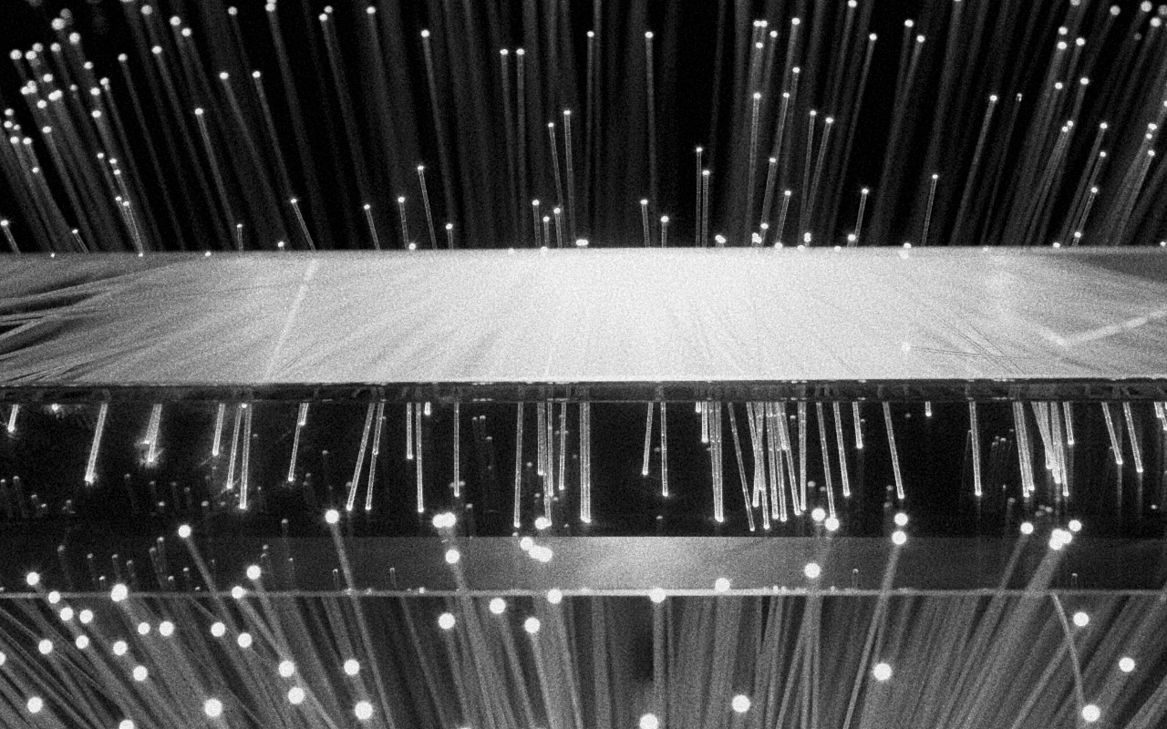 Close-up of illuminated fiber optic strands emitting light against a dark background.
