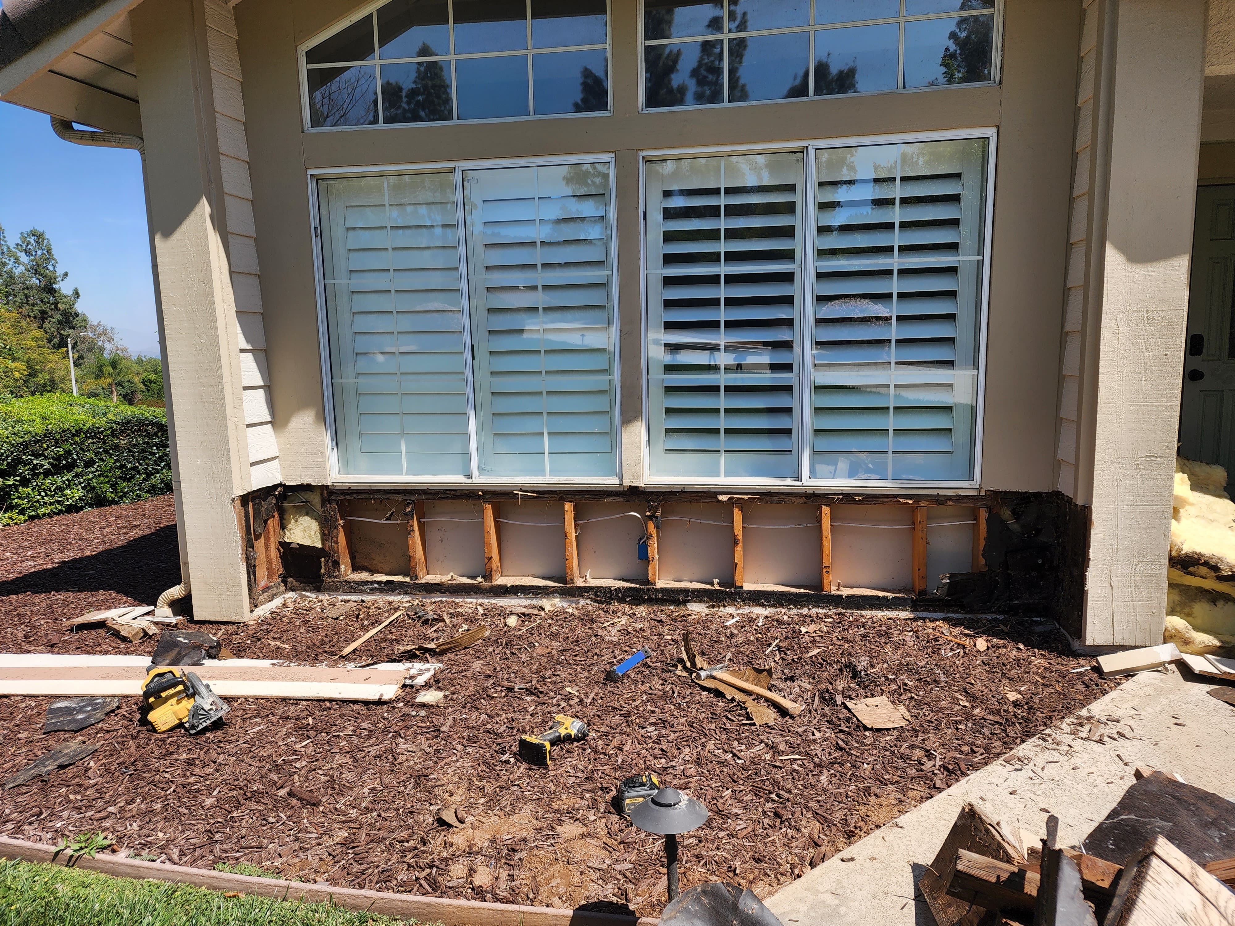 Damaged exterior wall beneath windows before repair