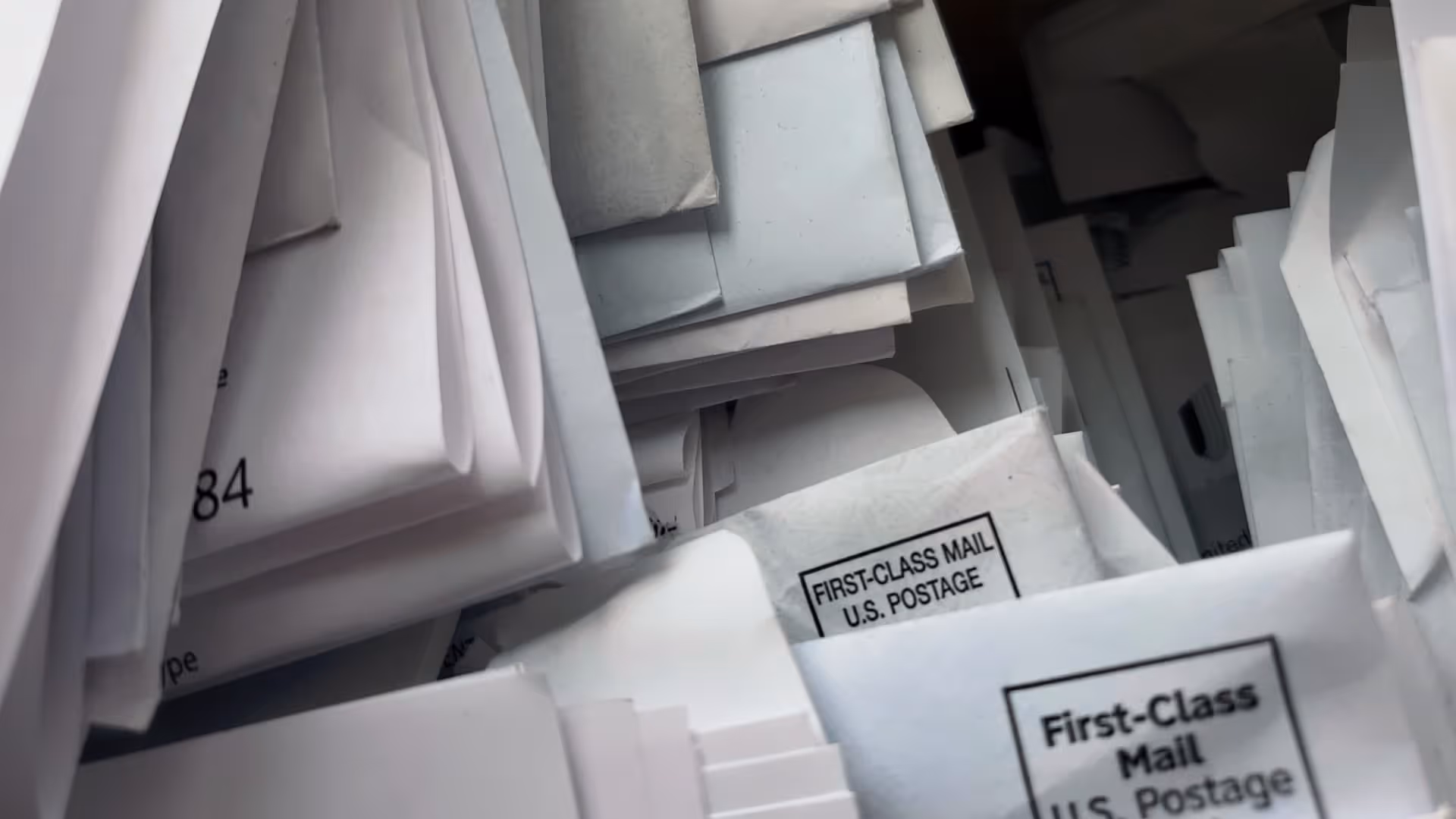Close-up overhead view of stacked first-class mail envelopes and bills.
