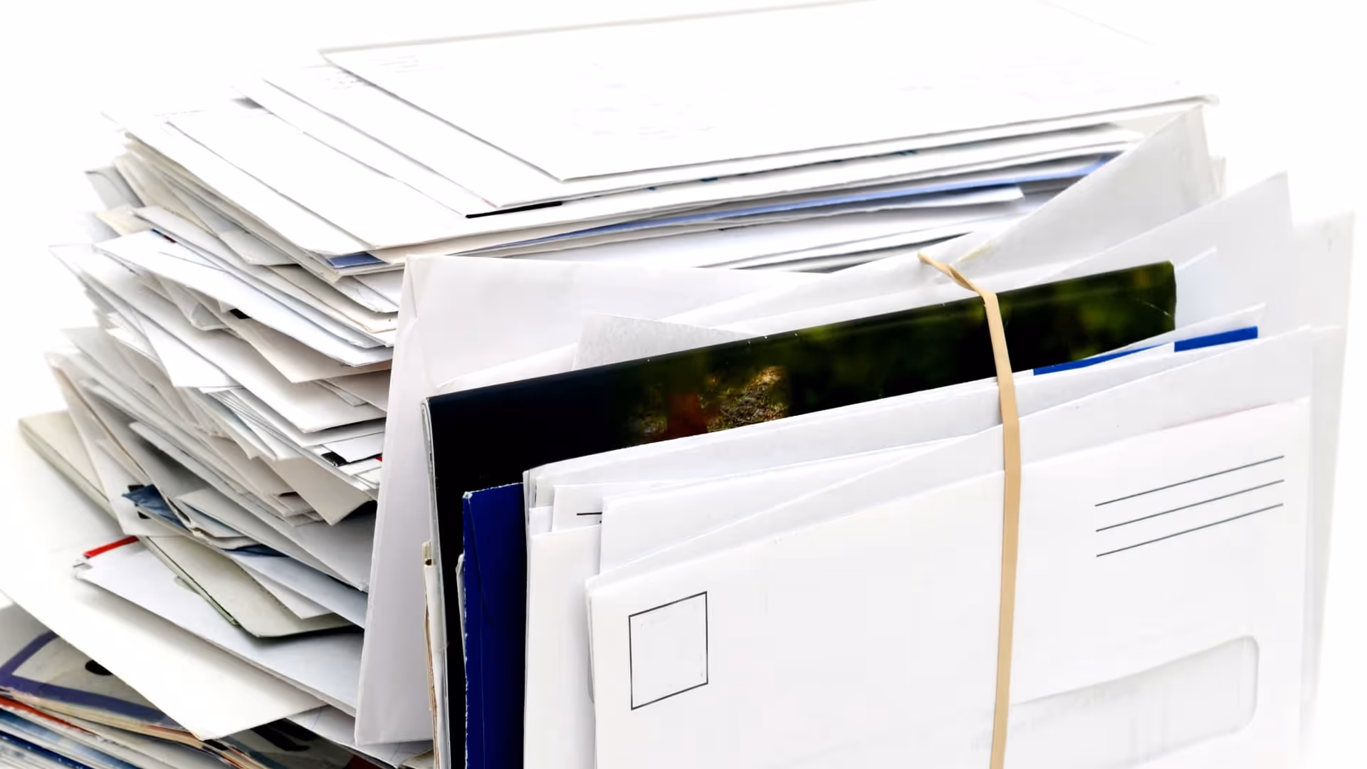 Stack of various envelopes and mail held together with a rubber band on a white background.
