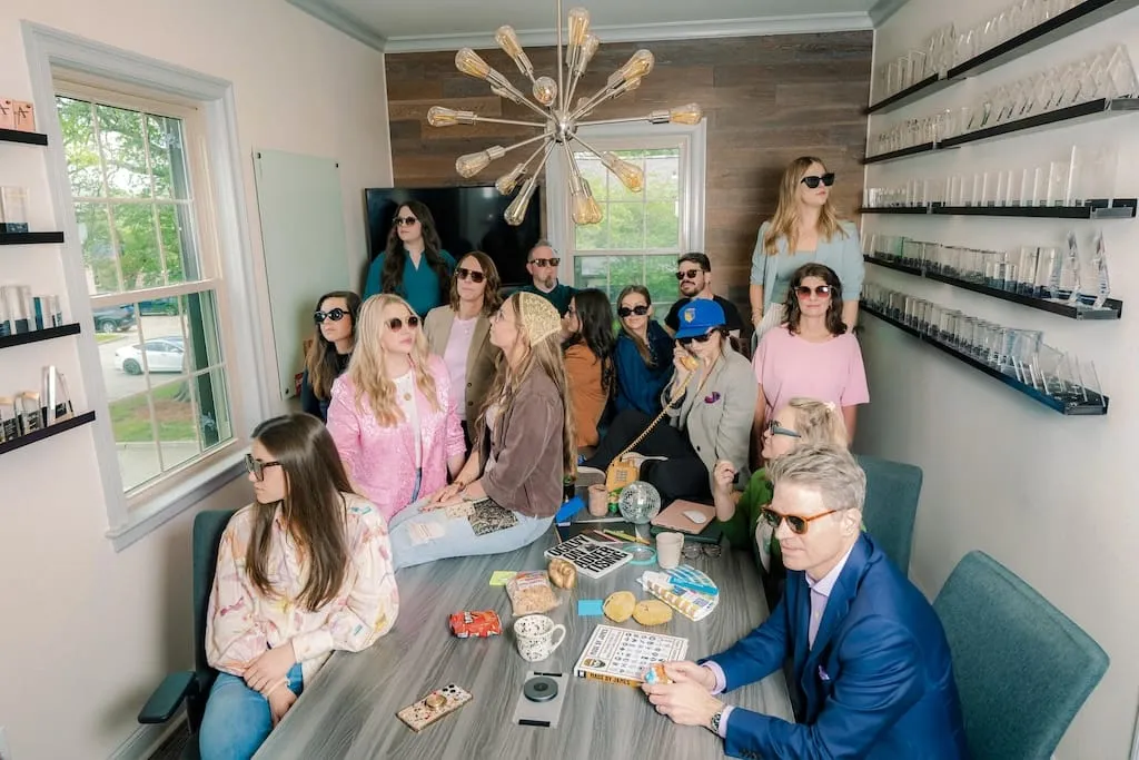 The MESH team seated around a conference table wearing sunglasses during a bingo game