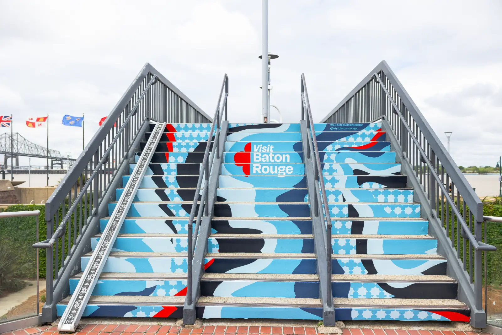 A public staircase painted with a bold blue and red Visit Baton Rouge mural