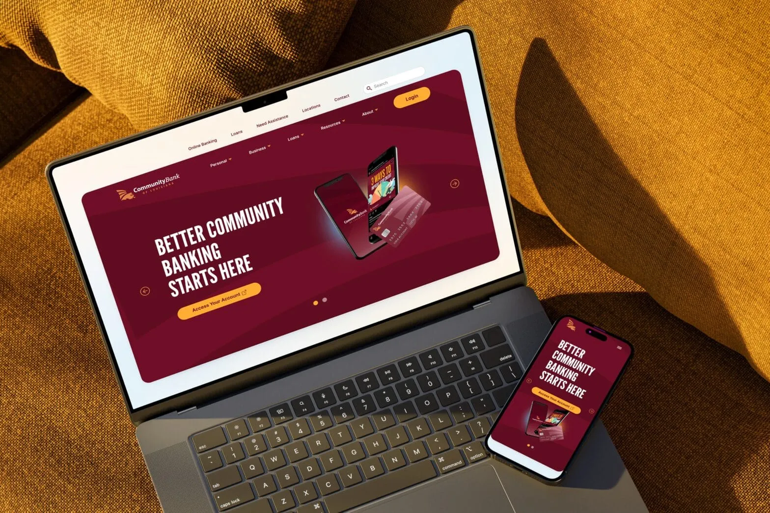 A laptop and phone on gold fabric showing a bank website headlined Better Community Banking Starts Here