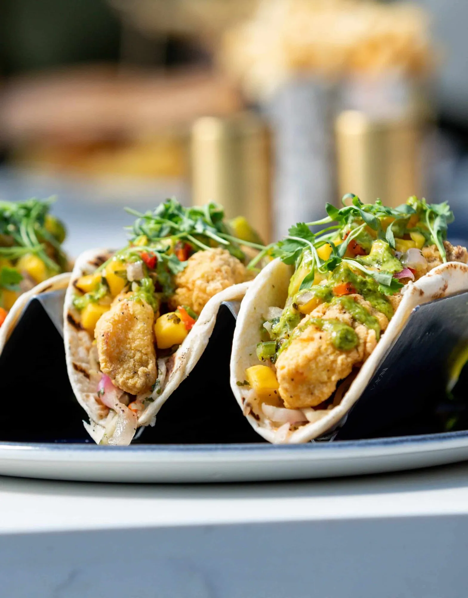 A plate of fried shrimp tacos topped with greens