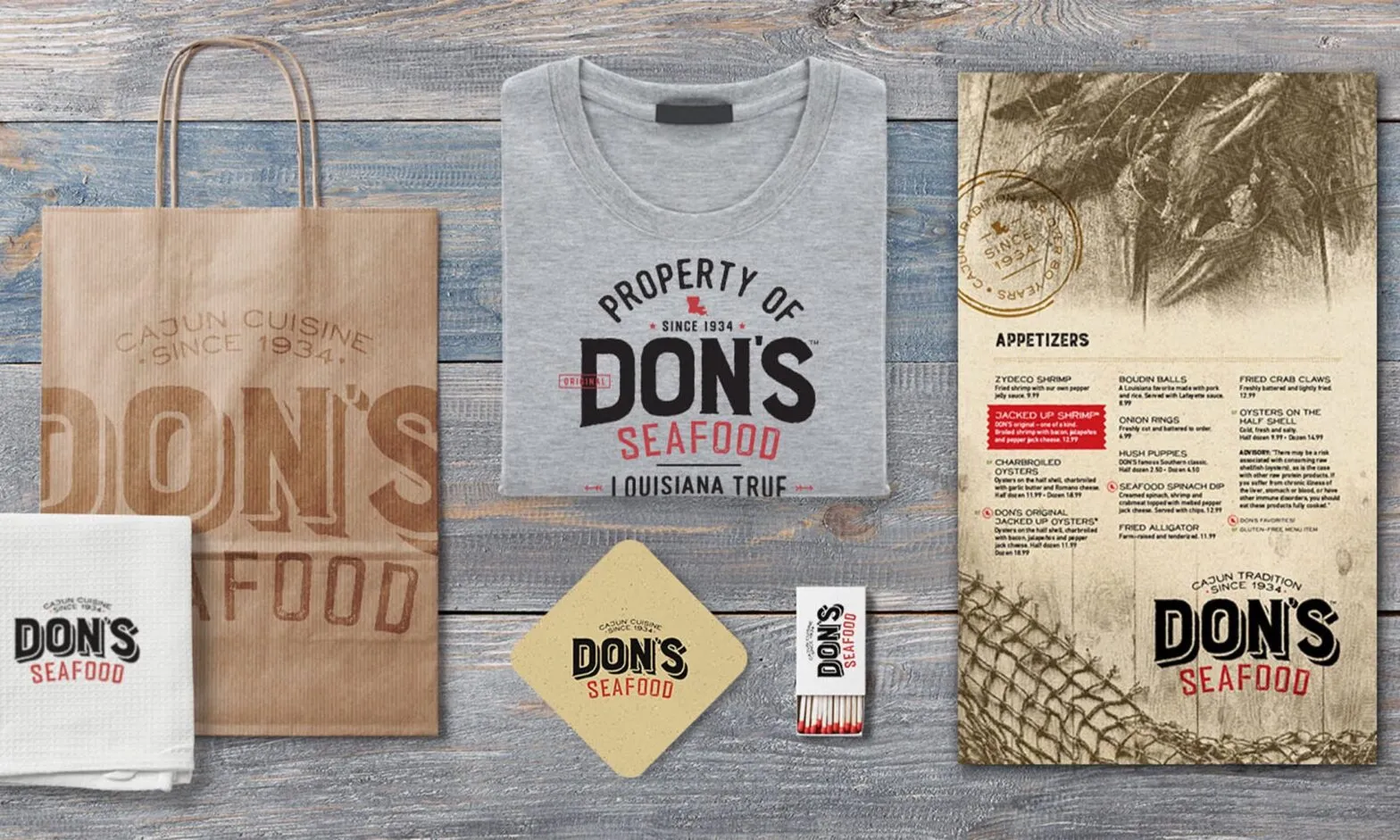 Don's Seafood branded packaging, a t-shirt, paper bags and matches laid out on wood