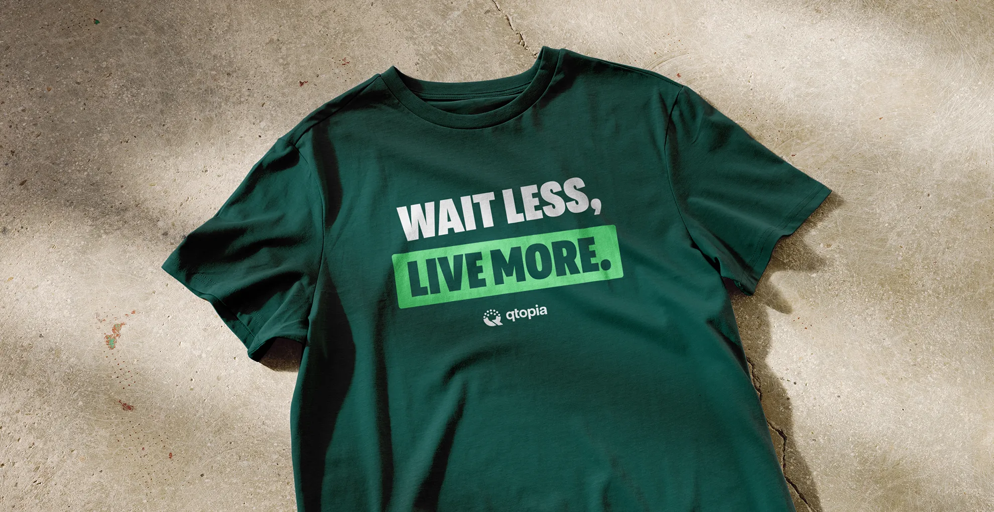 A green Qtopia t-shirt reading Wait Less, Live More