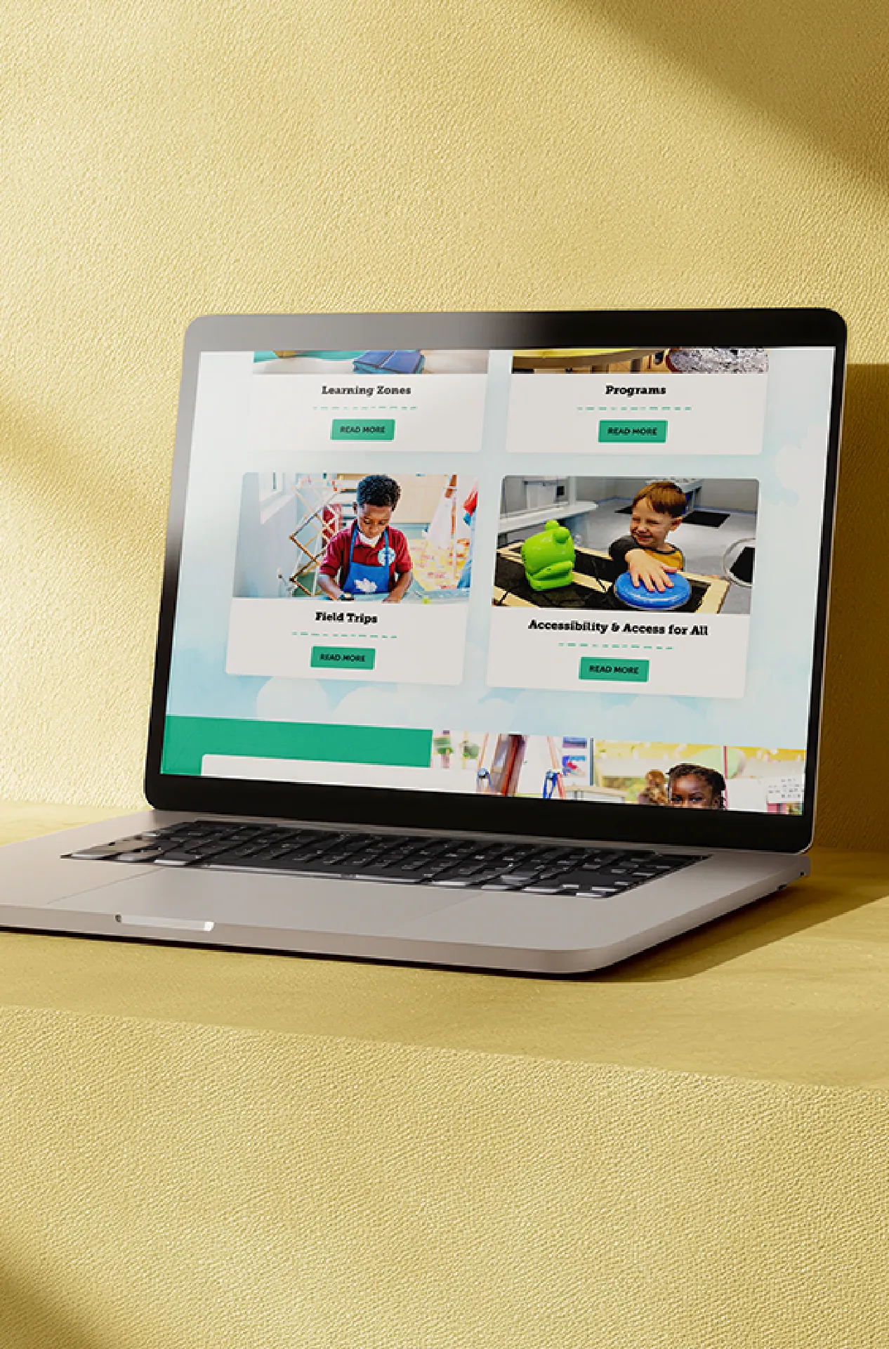 A laptop on a yellow background showing the Knock Knock Children's Museum website