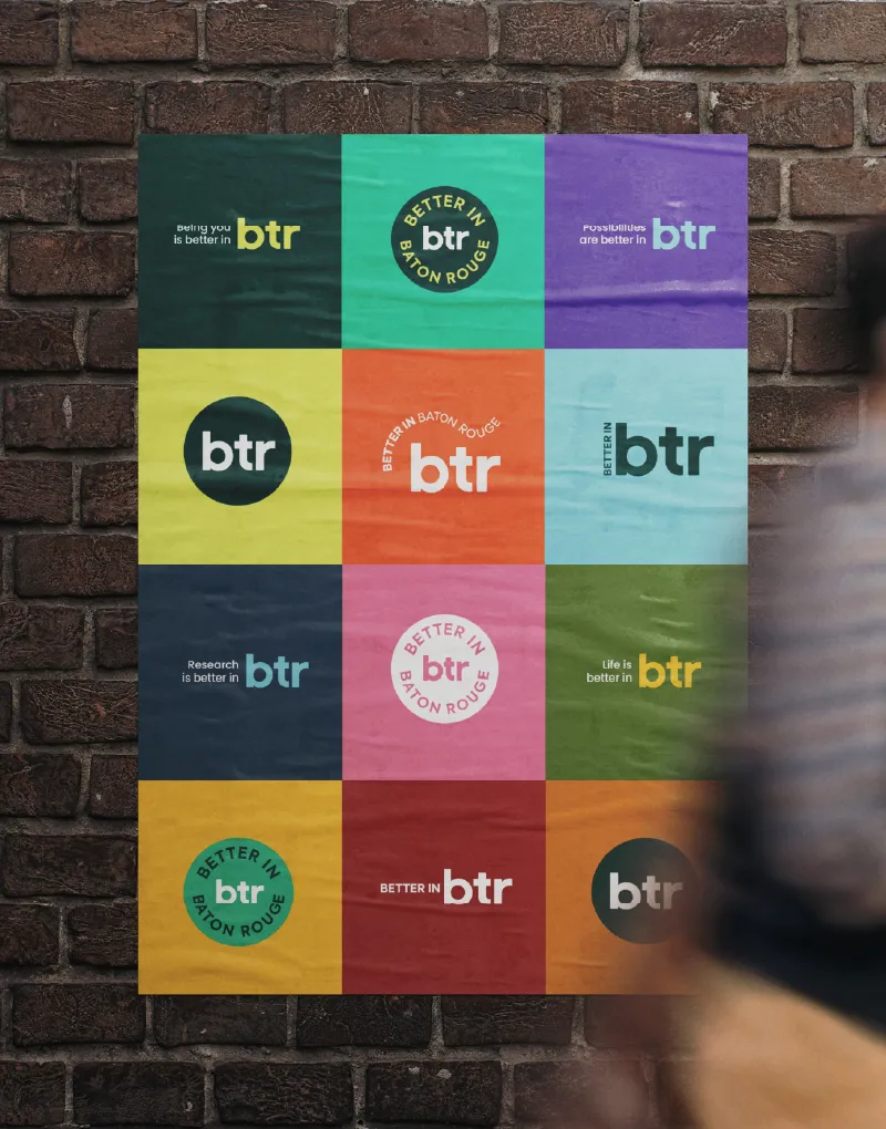 A poster on a brick wall showing a grid of colourful Better in BTR logo variations
