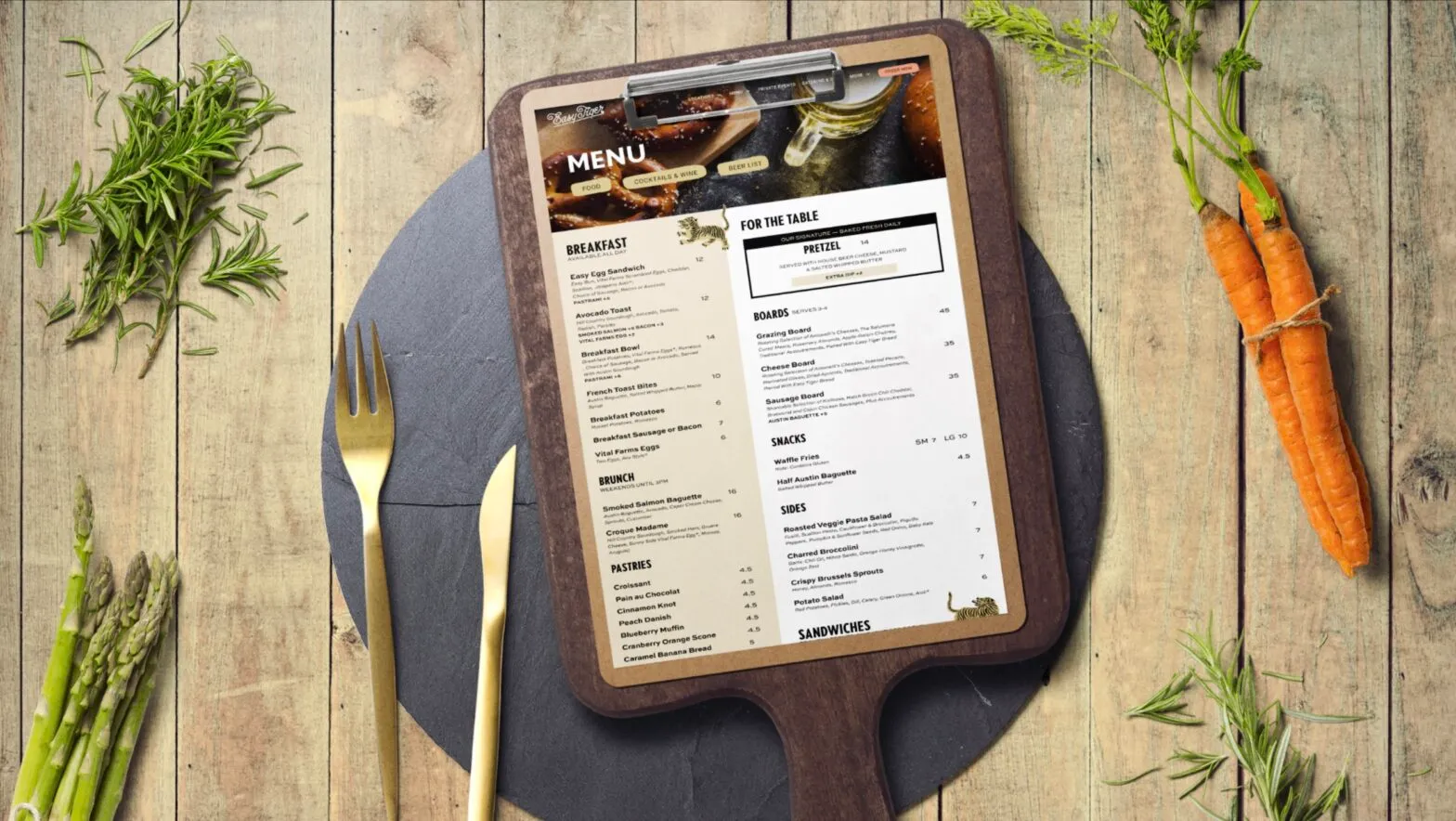 An Easy Tiger menu on a wooden board surrounded by fresh vegetables