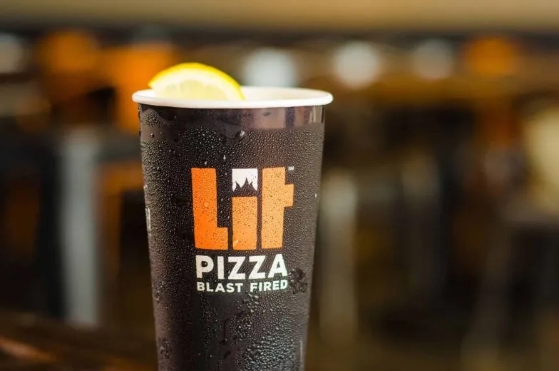 A LIT Pizza drink cup garnished with a lemon slice