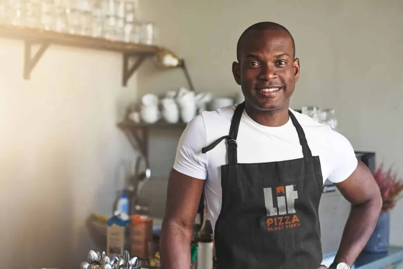 A LIT Pizza team member smiling in a branded apron