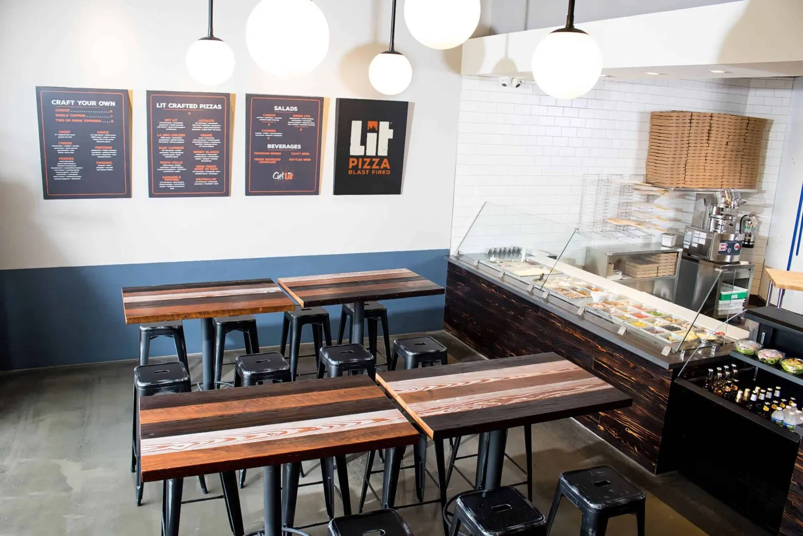 The interior of a LIT Pizza restaurant with counter seating and menu boards