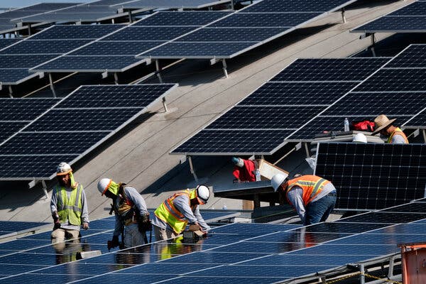 Workers install solar panels on the roof of the Van Nuys Airport in Los Angeles in 2019.