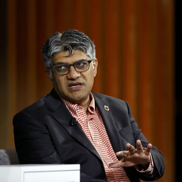 Jigar Shah, wearing a blazer over a red-and-white checked shirt, speaks at a conference.