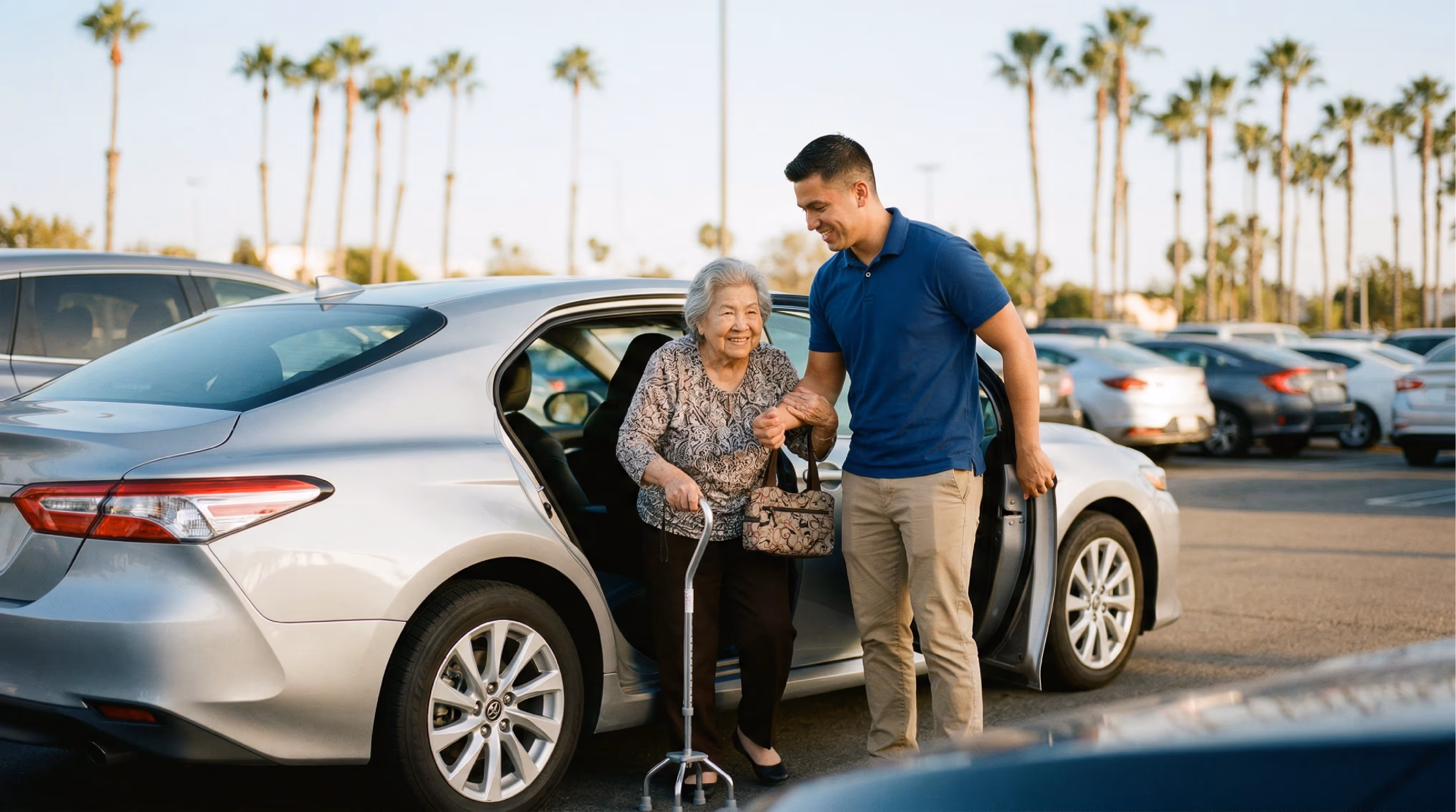 A male caregiver helping an elderly man out of the back seat of a car.