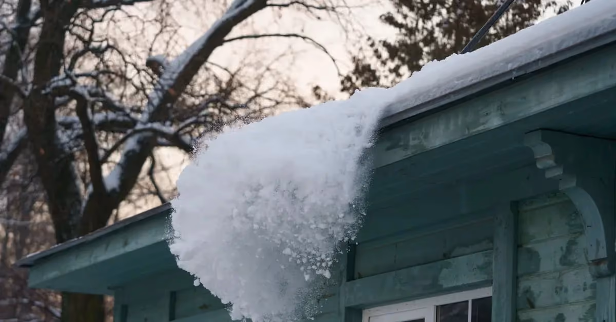 Snow buildup on roof edge creating ice dam near gutter during winter