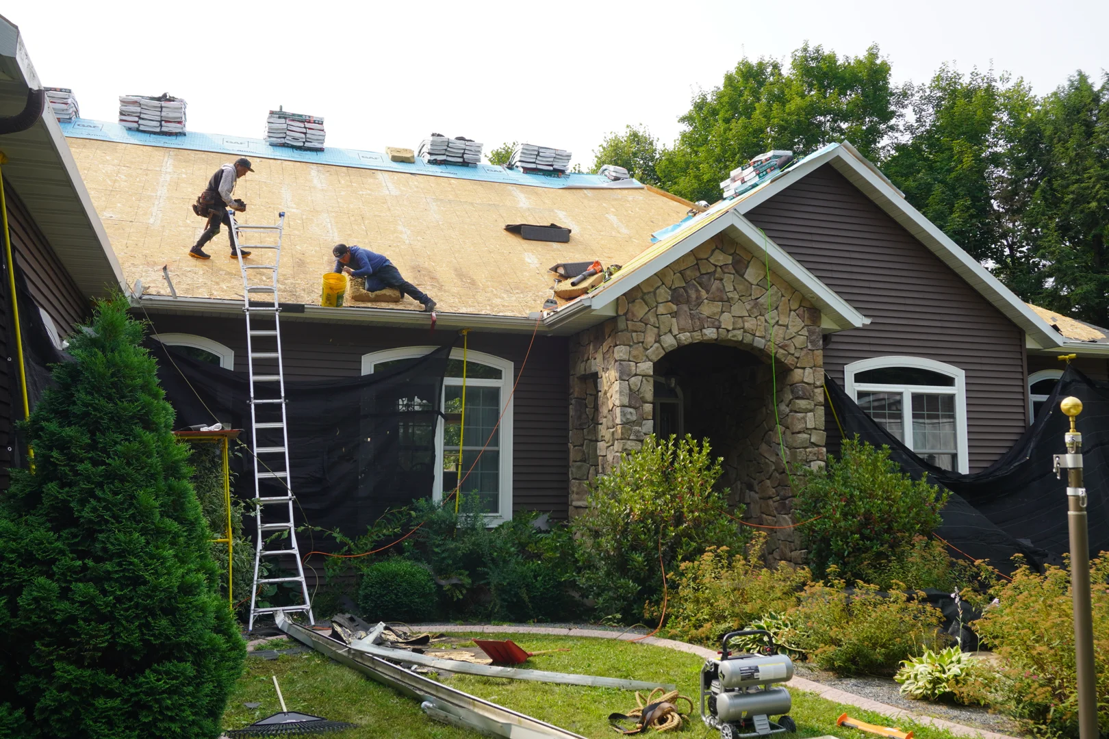 A-RITE Exteriors crew member cleaning debris from gutters safely on a ladder