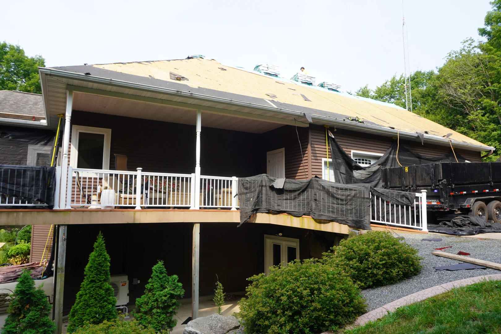 roofing crew protecting landscaping with tarps during a local roof replacement