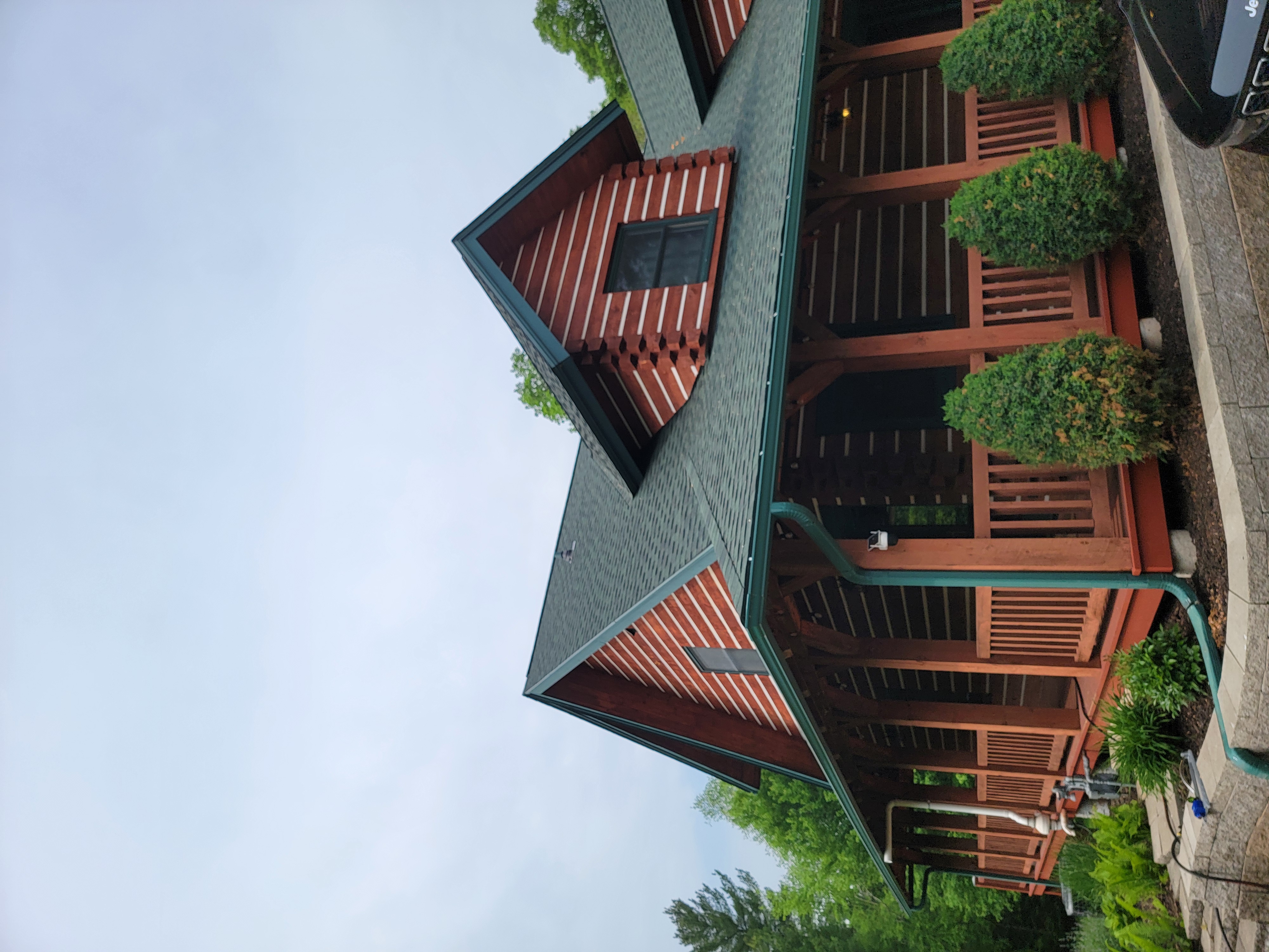 Angled view of a GAF Hunter Green roof on a Mosinee, WI log-style home with green trim and gutters.