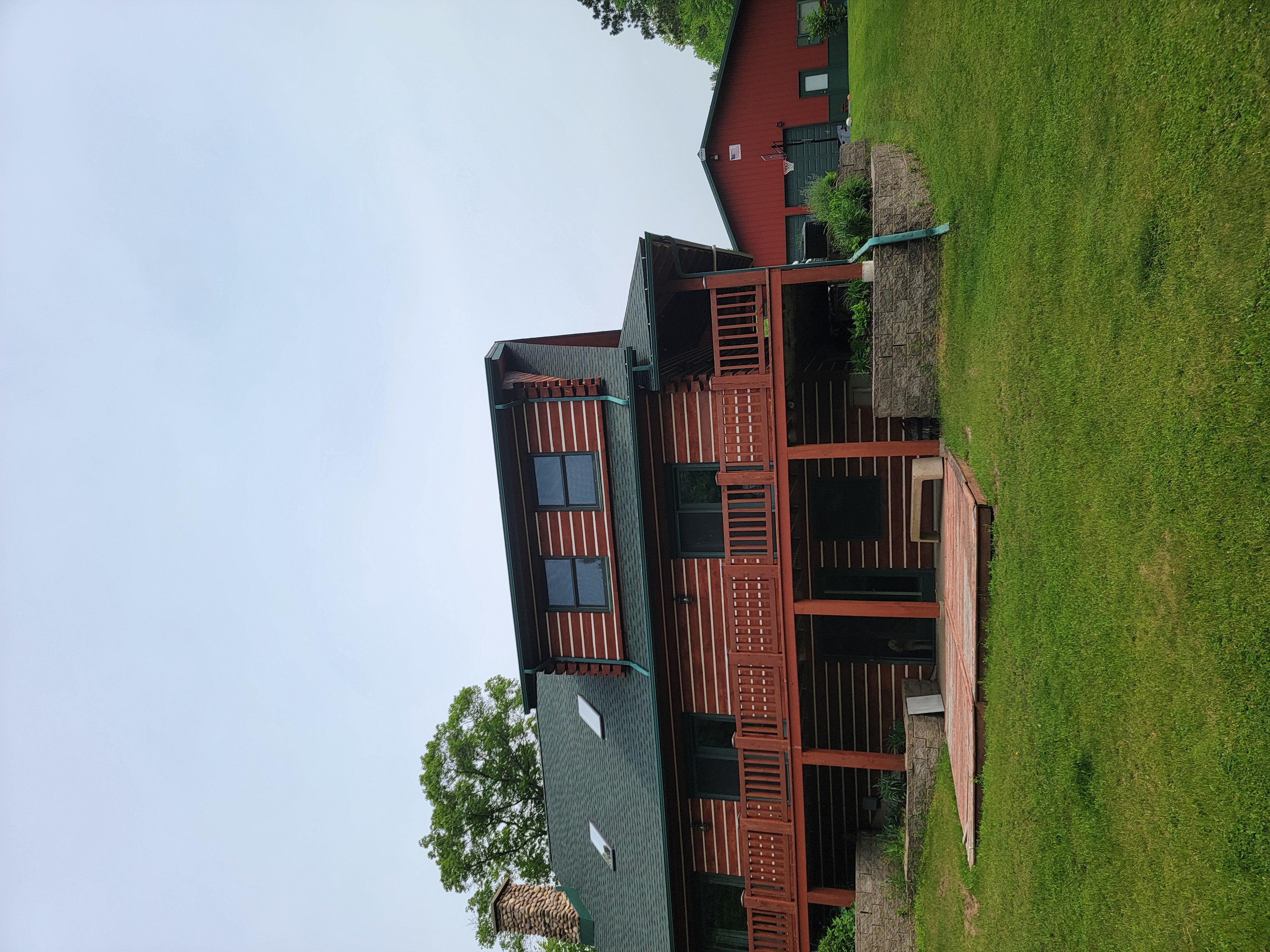 Finished GAF Hunter Green roof replacement in Mosinee, WI on a log-style home with a large front porch.