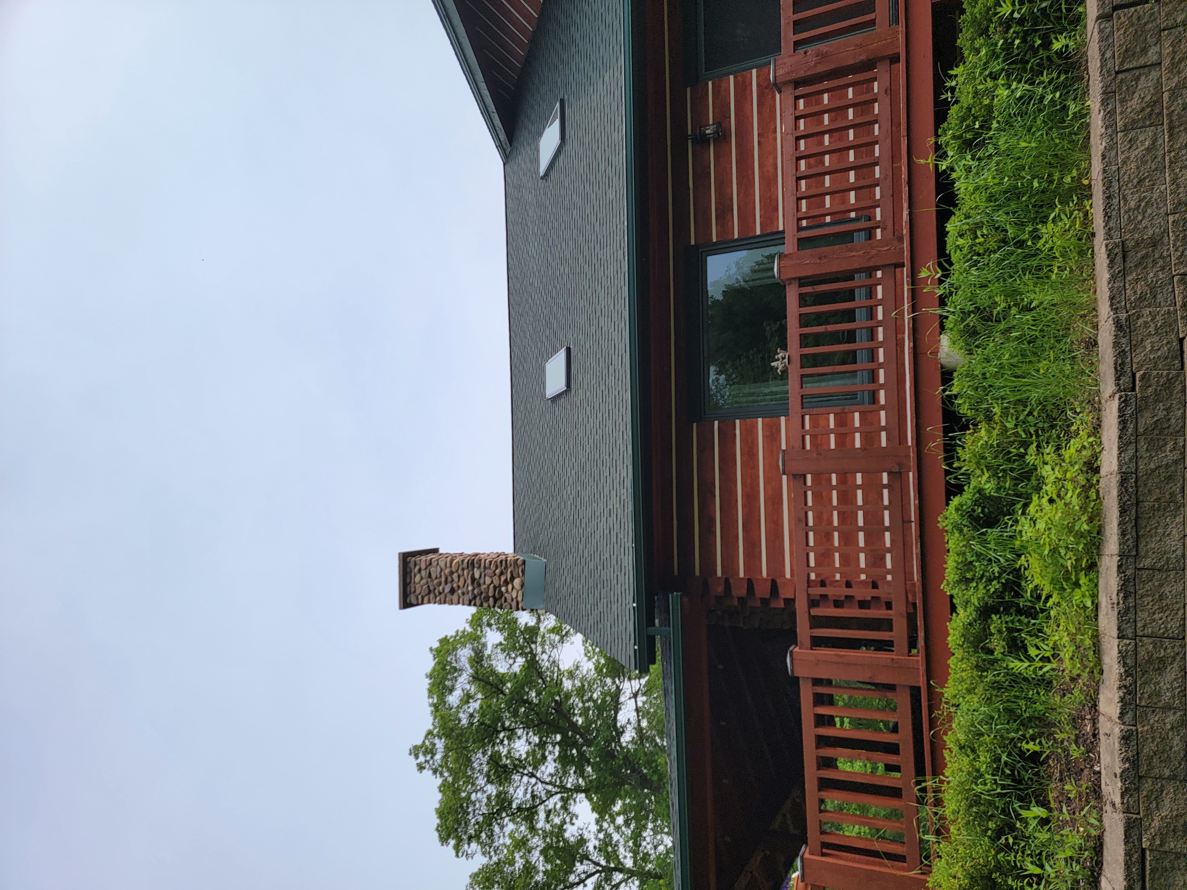 Back side of a Mosinee, WI home showing a GAF Hunter Green roof with skylights, dormer, and green gutters.