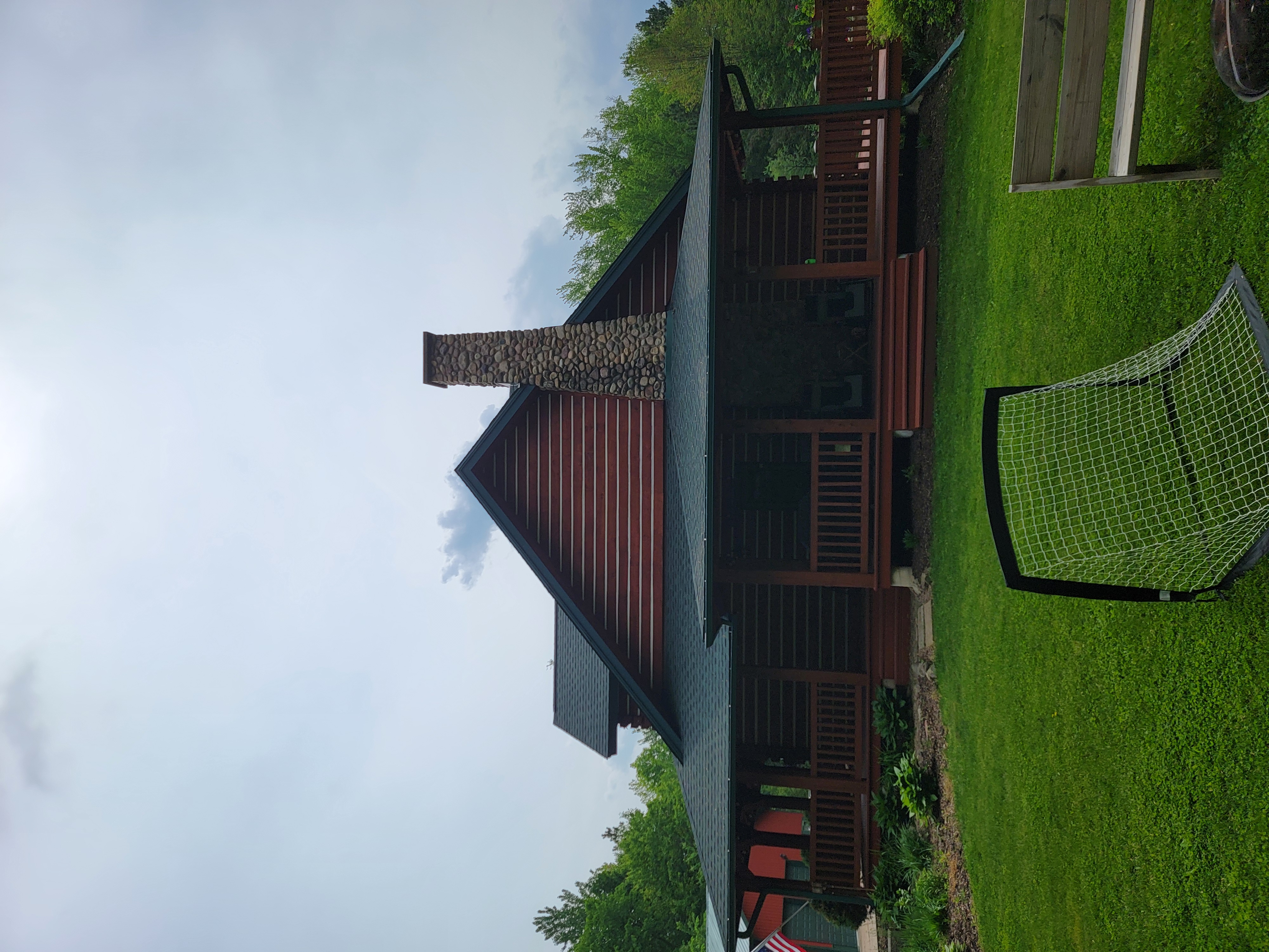 GAF Hunter Green roof replacement in Mosinee, WI with skylights, stone chimney, and rear deck view.