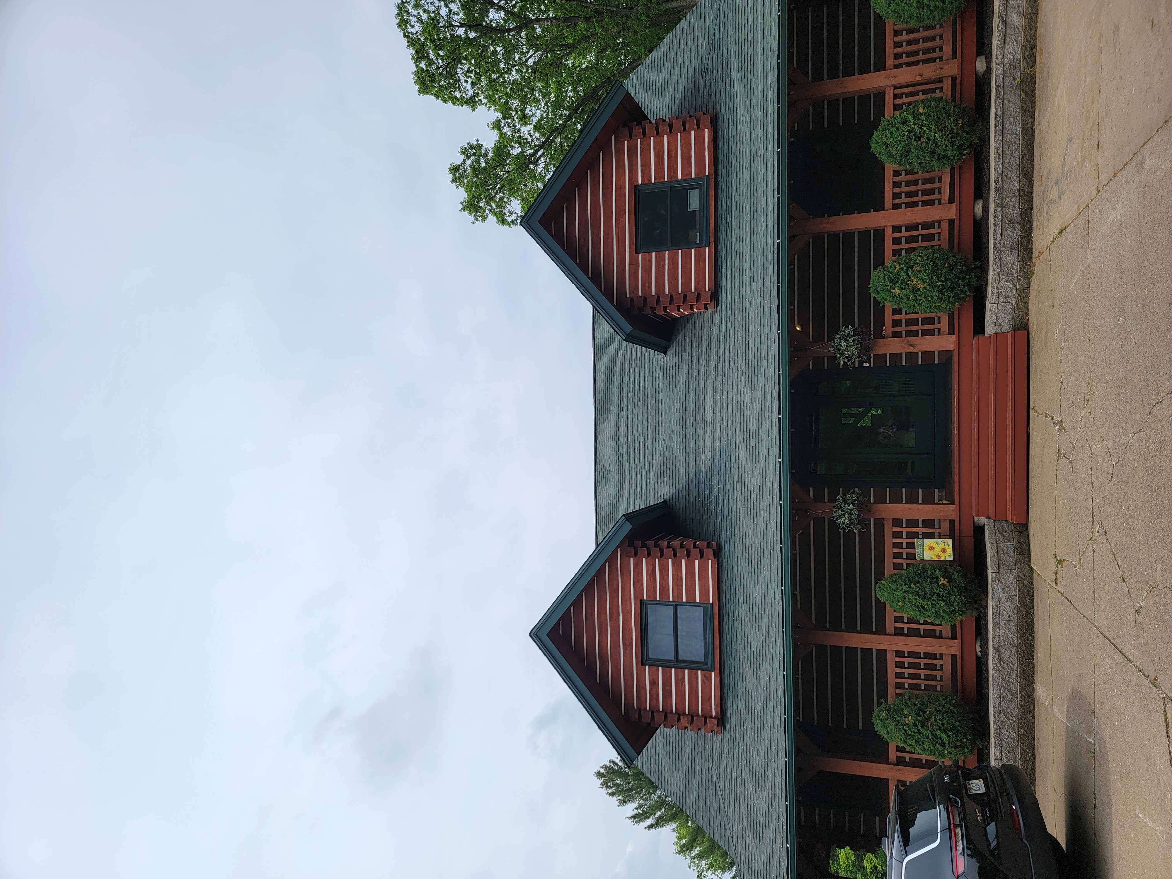Finished Hunter Green roof on a Mosinee, WI log-style home with stone chimney, porch, and wooded yard.