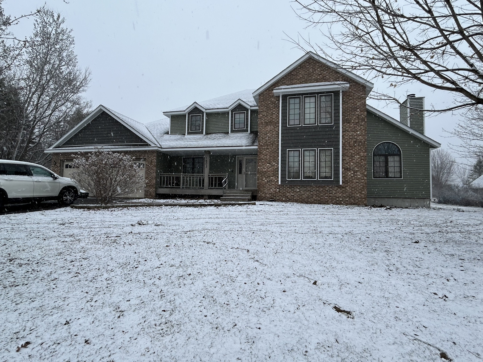 Finished Norandex Olive siding project in Schofield, WI with brick front, white trim, and snowy yard.