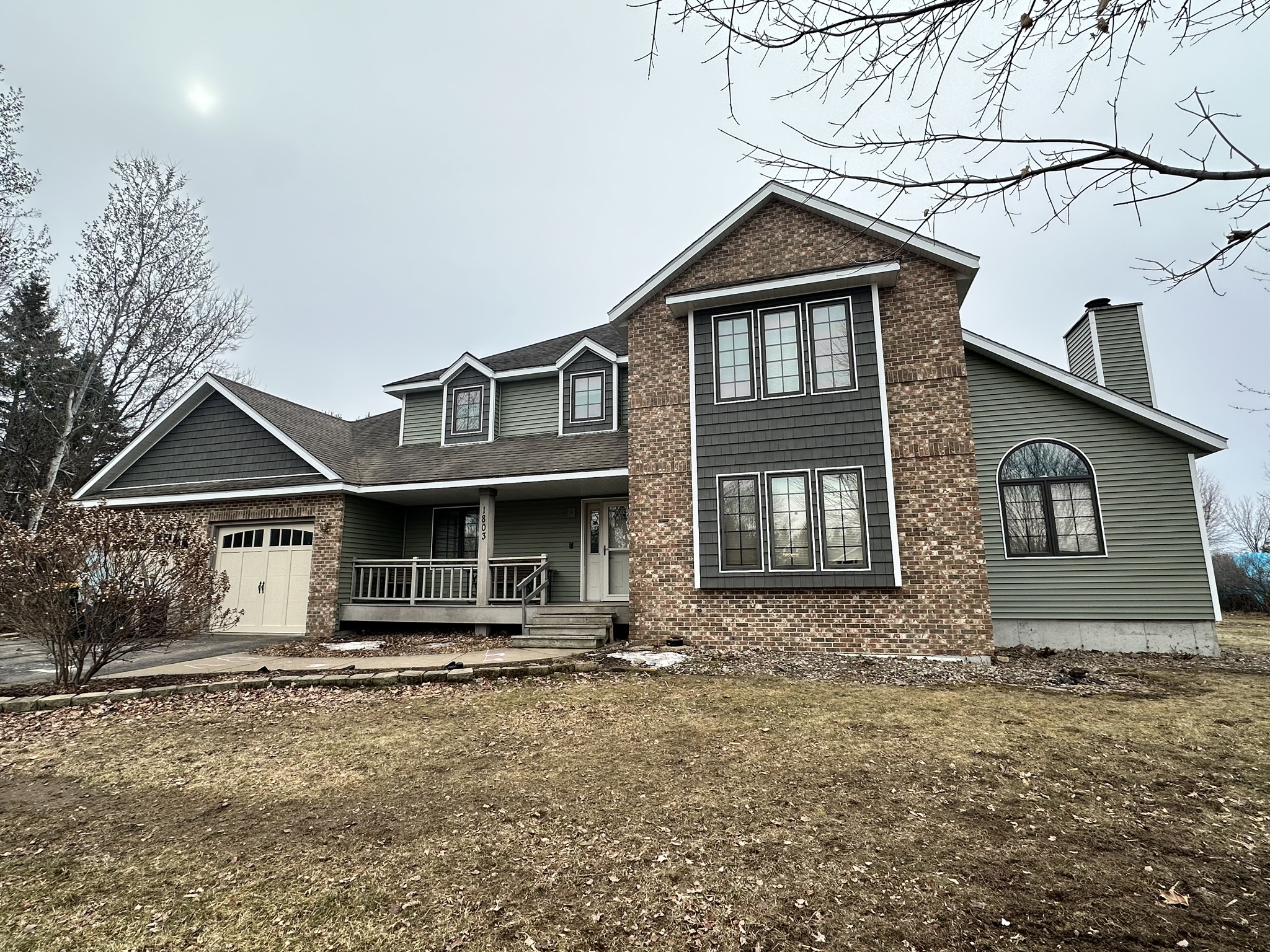 Completed Norandex Olive siding project in Schofield, WI with brick accents and black window trim.