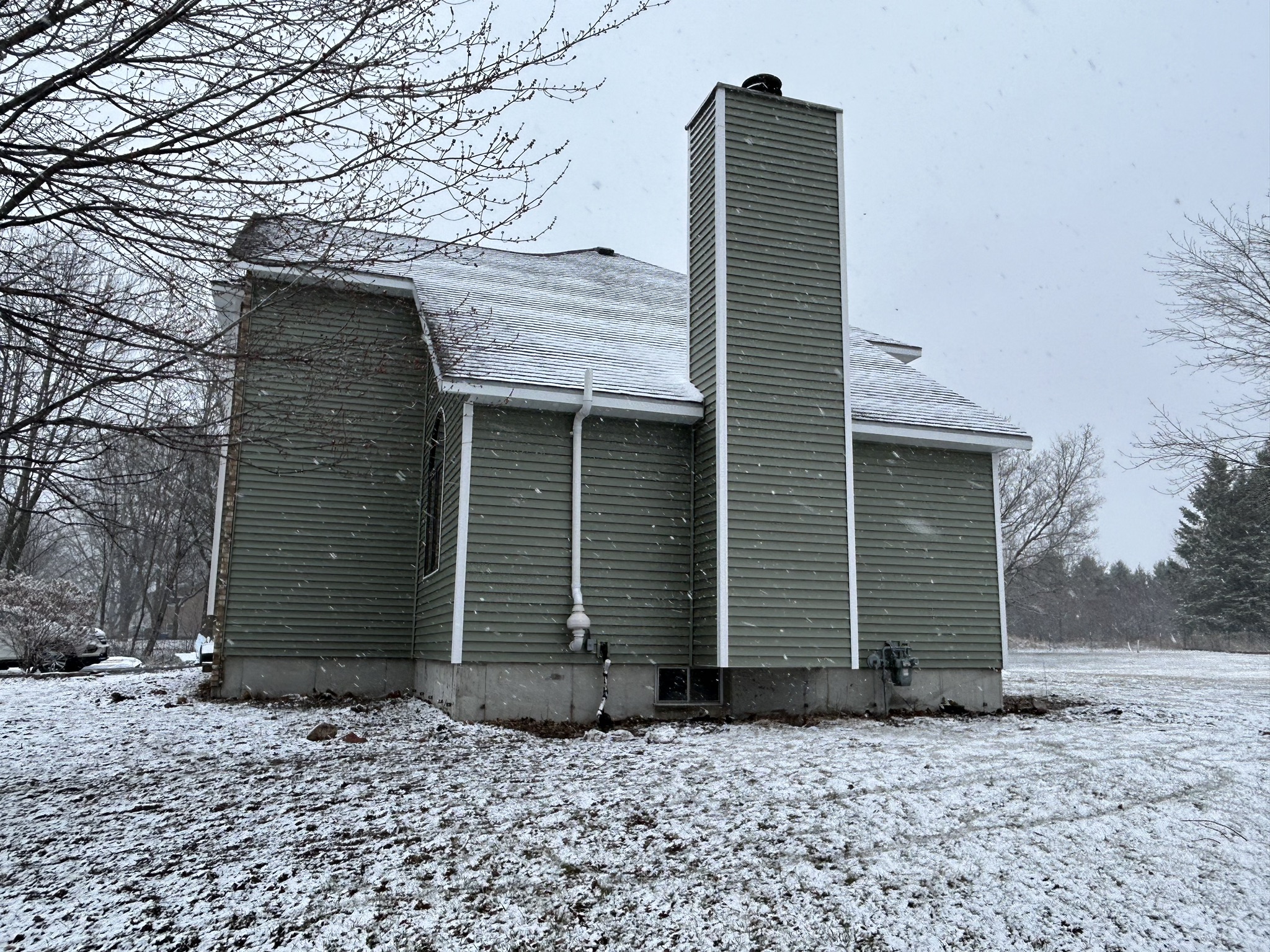 Side view of Norandex Olive siding on a Schofield, WI home with white trim and chimney details.