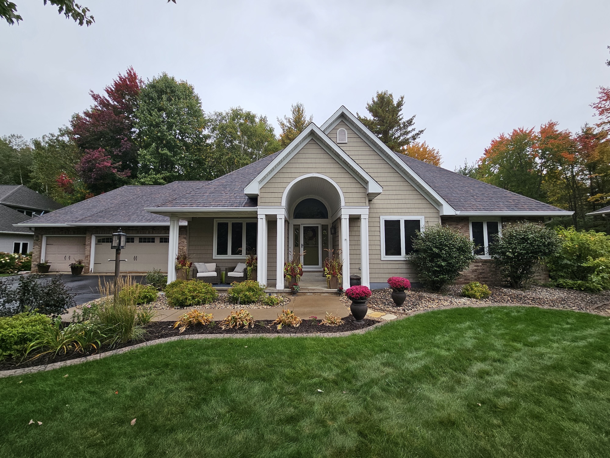 Front view of a Wisconsin home with a brown architectural shingle roof, brick accents, white trim, and landscaped yard.