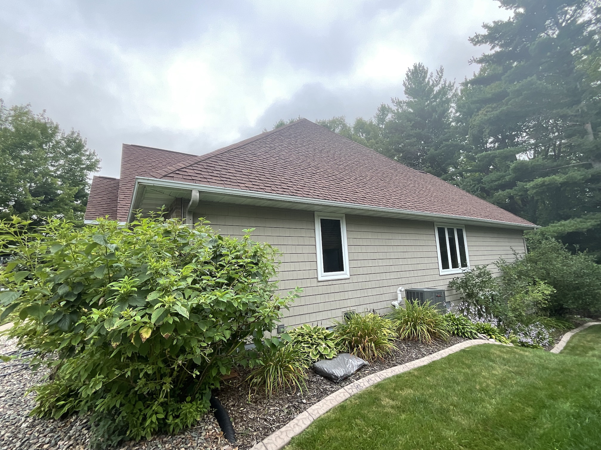 Before roof replacement on a Wisconsin home showing the older roof before new brown architectural shingles were installed.