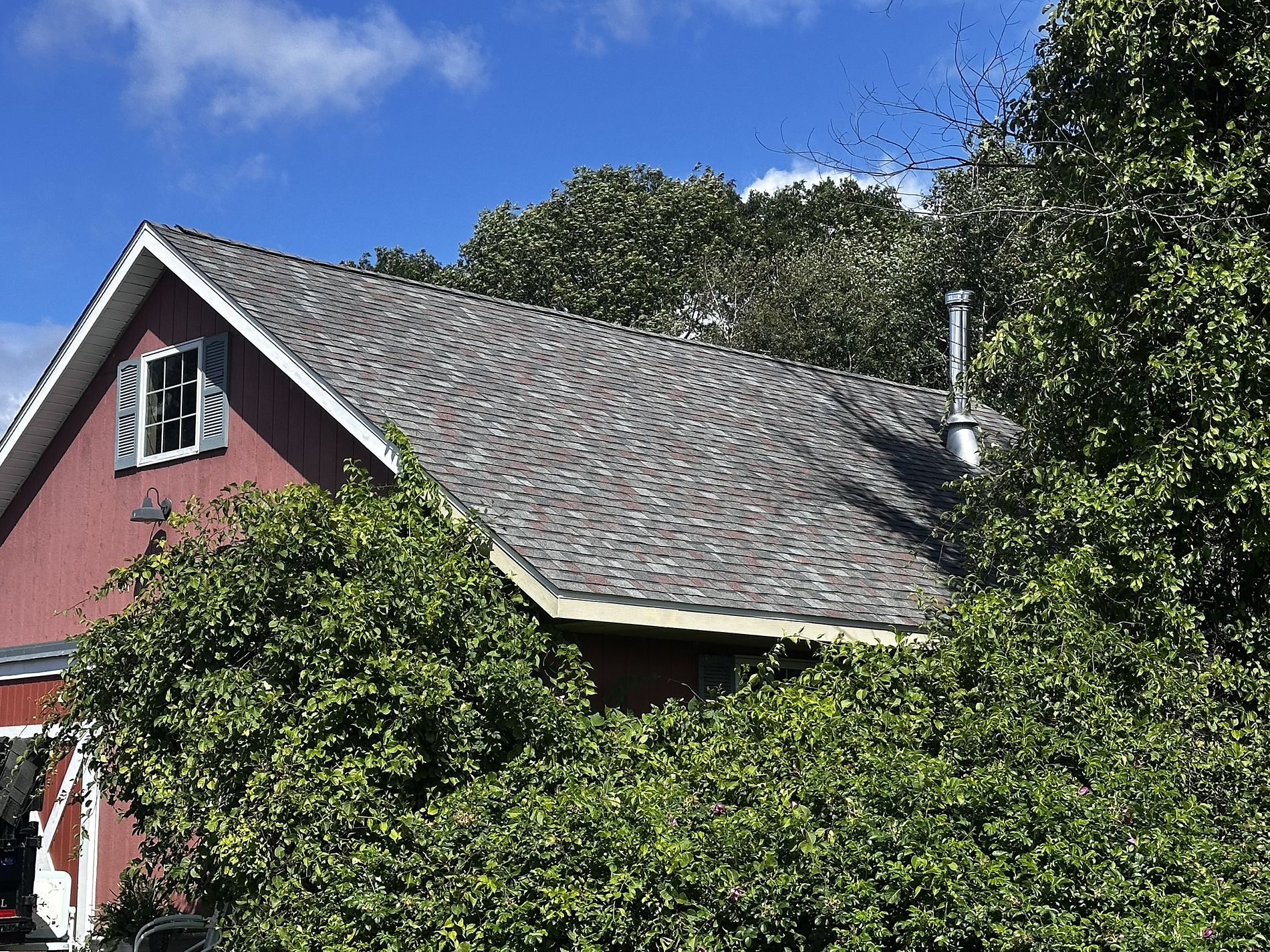 Brown architectural shingle roof replacement in Wausau, WI on a barn-style garage surrounded by mature trees and greenery.