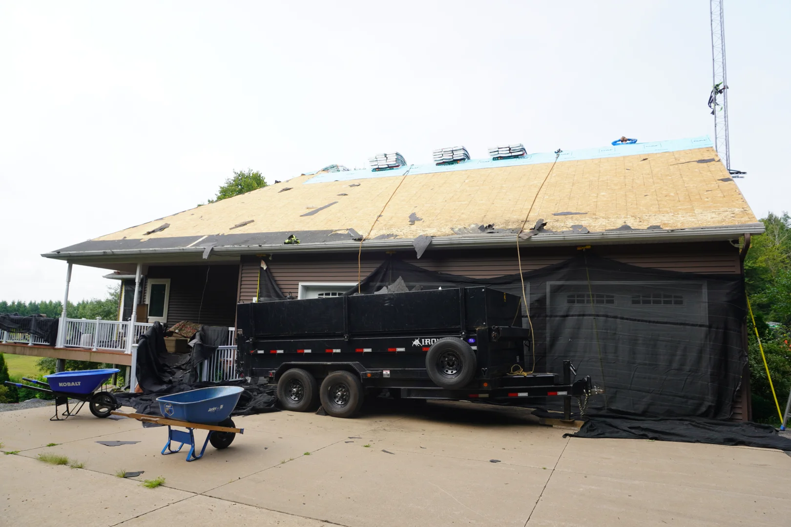 Roofing crew tearing off old shingles and installing new underlayment Roofing crew tearing off old shingles and installing new underlayment
