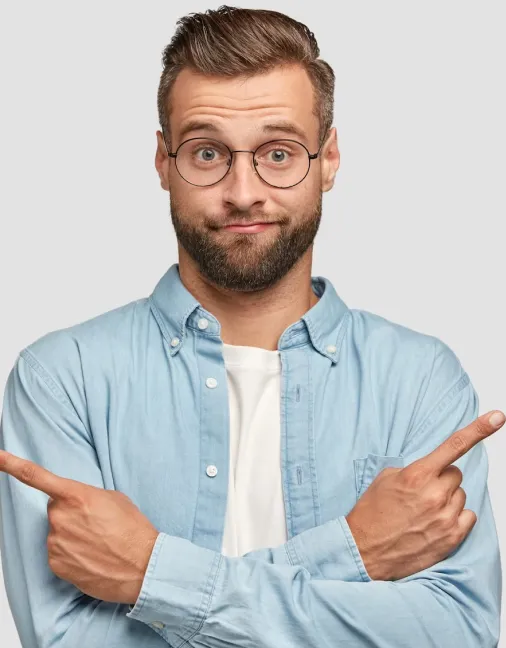 Man with glasses and beard wearing a light blue shirt, crossing arms and pointing fingers in opposite directions with a puzzled expression.