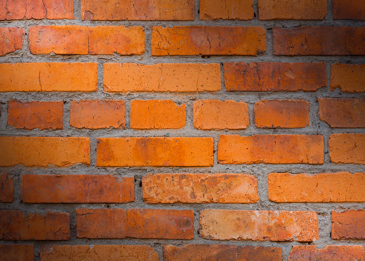 Close-up of a brick wall with orange-red bricks and gray mortar.