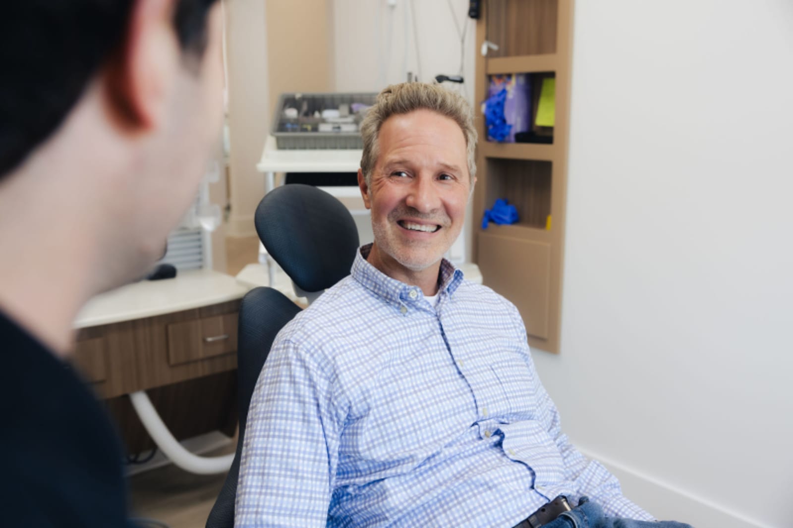 Male dentist consulting with patient in clinical setting at Evelina Smiles