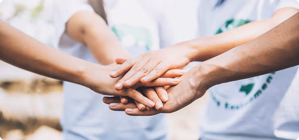 Close-up of multiple hands stacked together in a gesture of teamwork and unity.