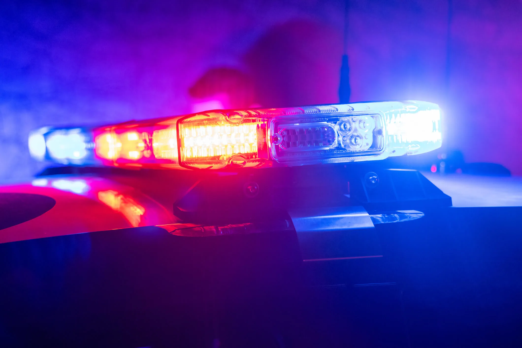 Red and blue emergency lights on a police car light bar at night