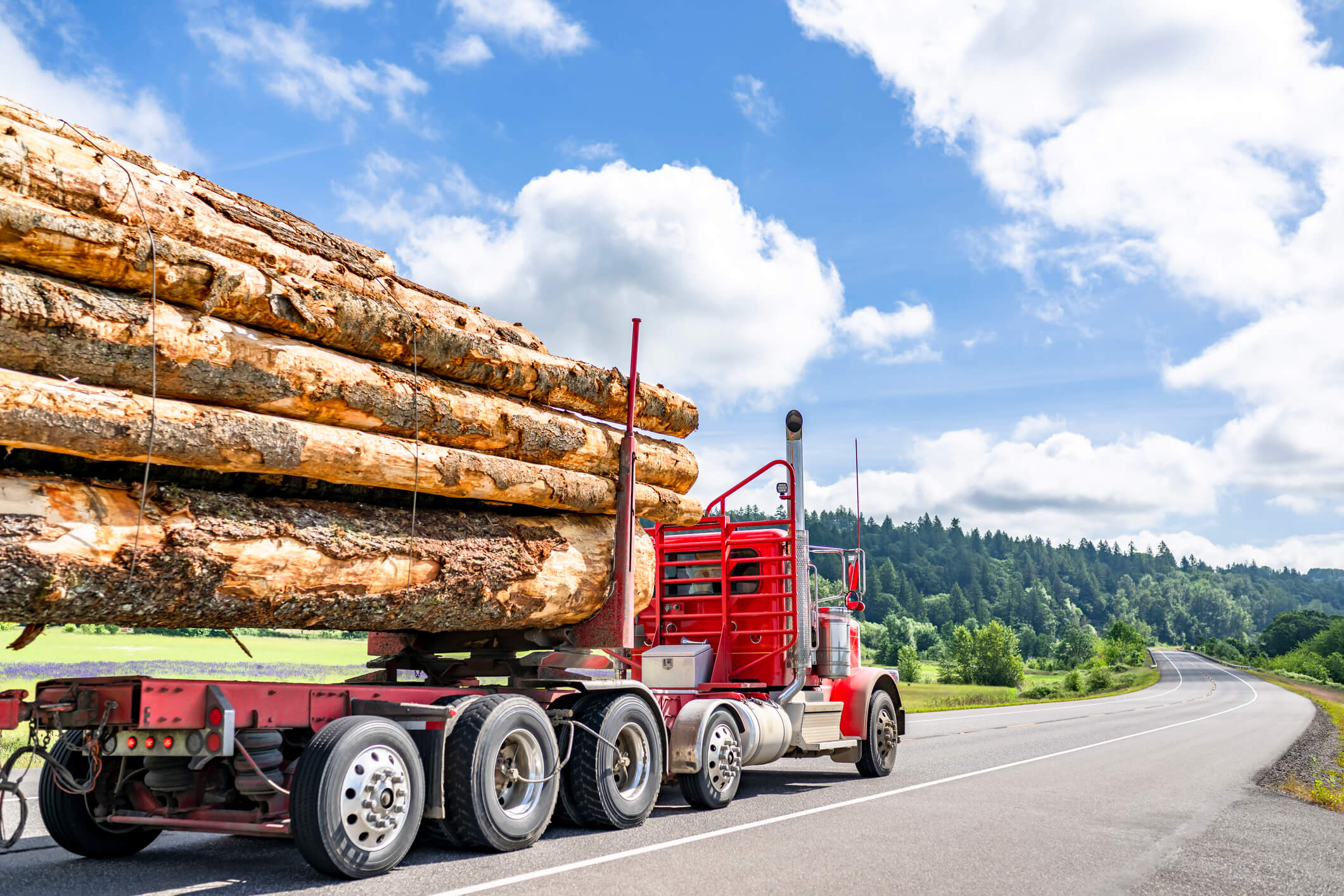 Red logging truck hauling timber on a highway — personal injury truck accident recovery