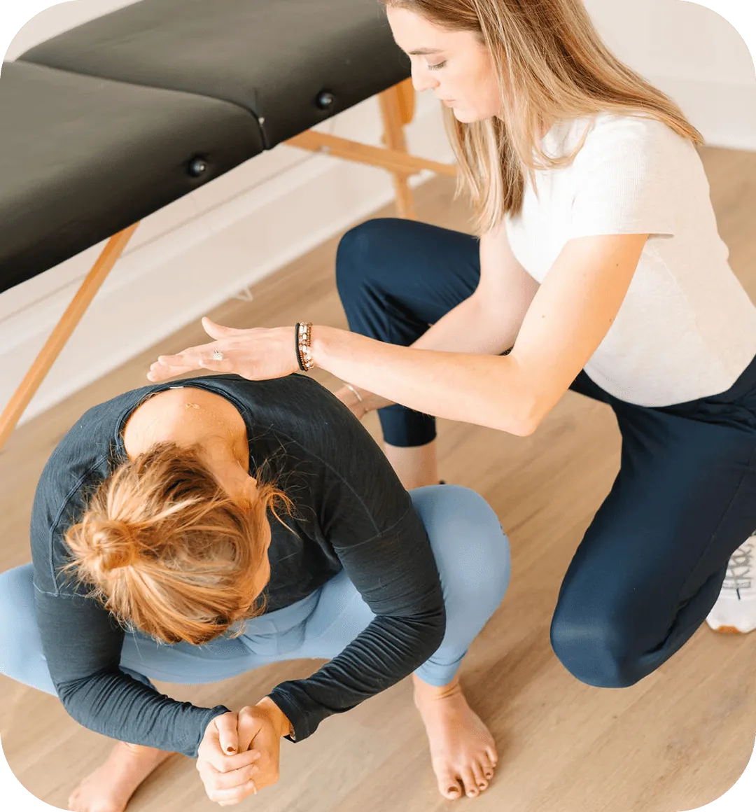Dr. Lynne DiPirro guiding a woman through a deep squat stretch on the floor during pelvic floor therapy