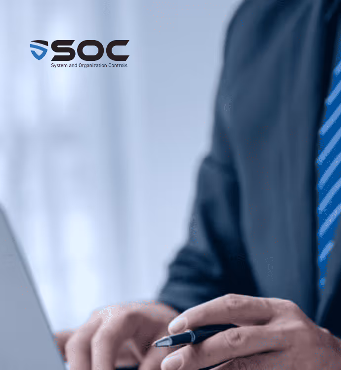 Eine Person in Geschäftskleidung hält einen Stift und arbeitet an einem Laptop, auf dessen Bildschirm das SOC-Logo zu sehen ist.